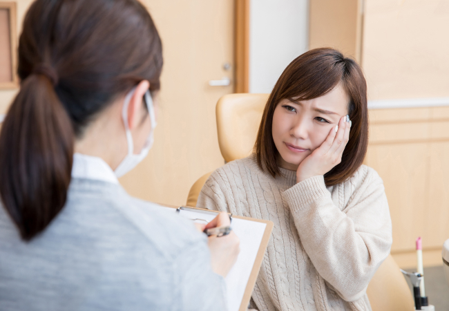歯の痛みを相談する女性と歯科スタッフ